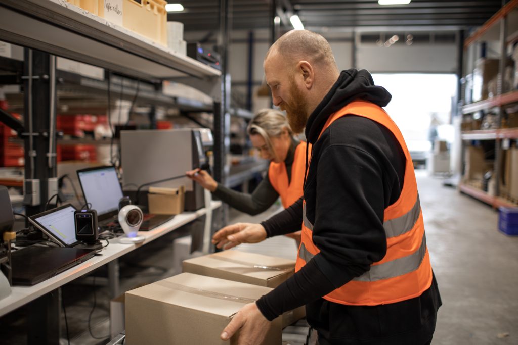 Two warehouse workers on a packing and delivery production line